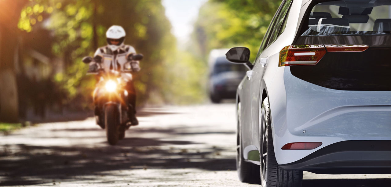 A motorcycle and a car pass each other