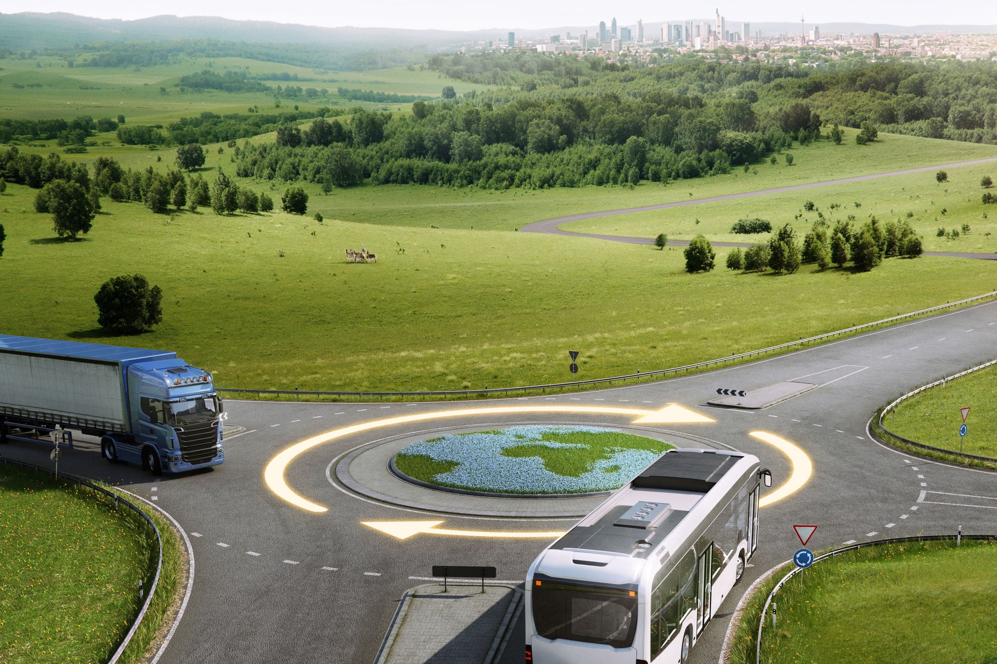 A bus and a truck approach a circular intersection with a grass design resembling Earth in the center. 