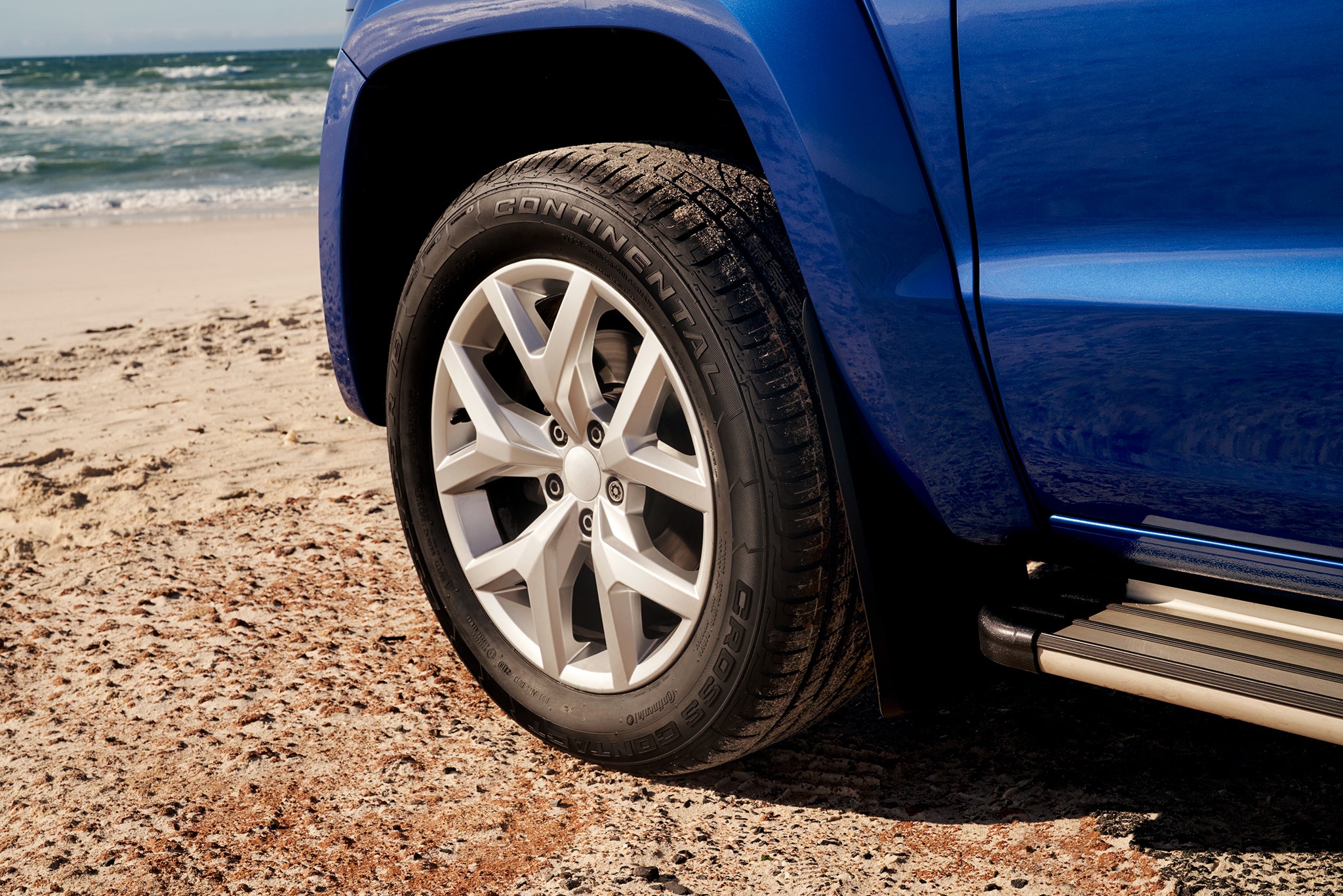 Blue pick-up truck equipped with Continental CrossContact tires at the beach.