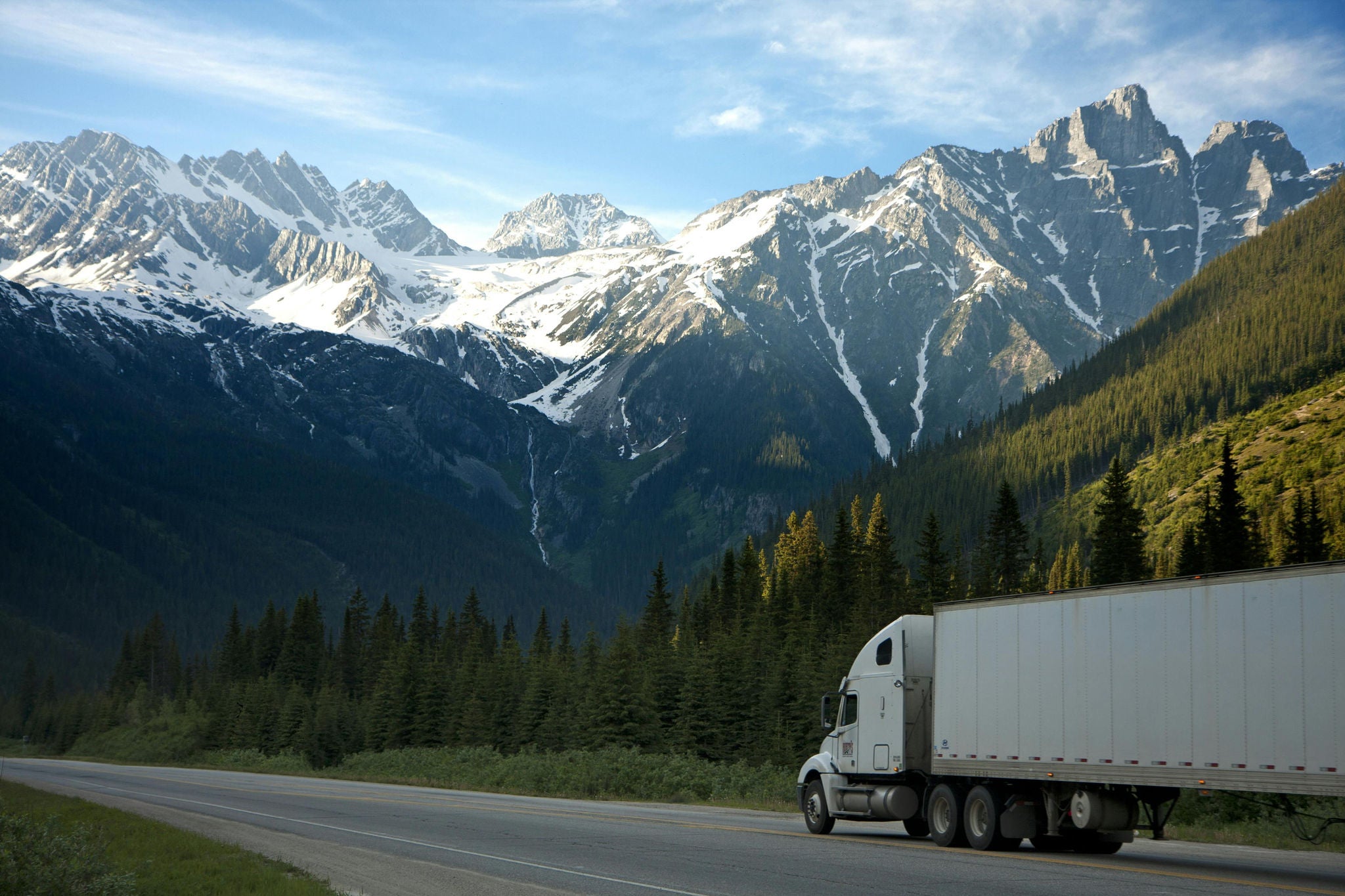 A truck on the road with mountains in the background 