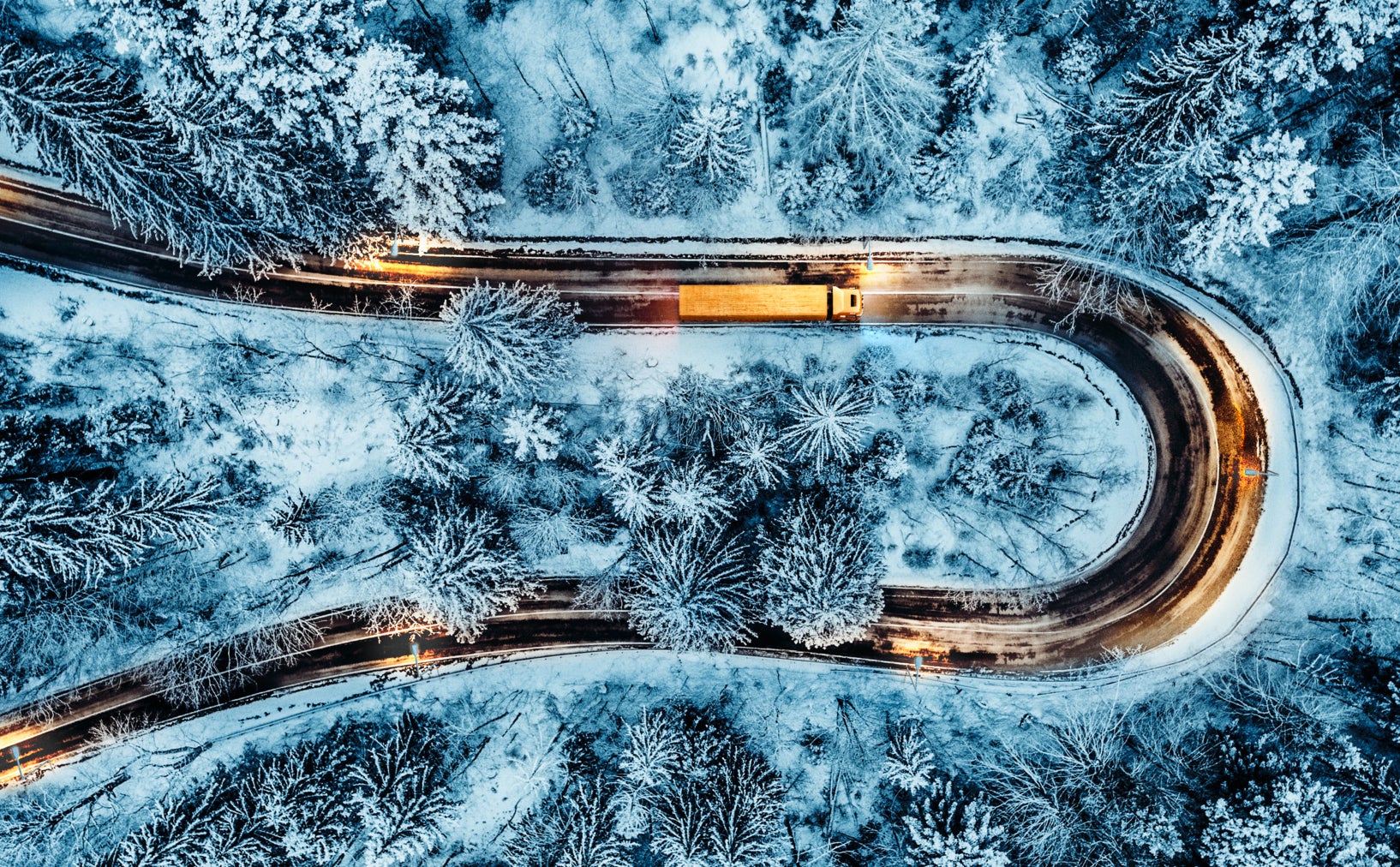 White car passing on an extreme winding road in wintertime