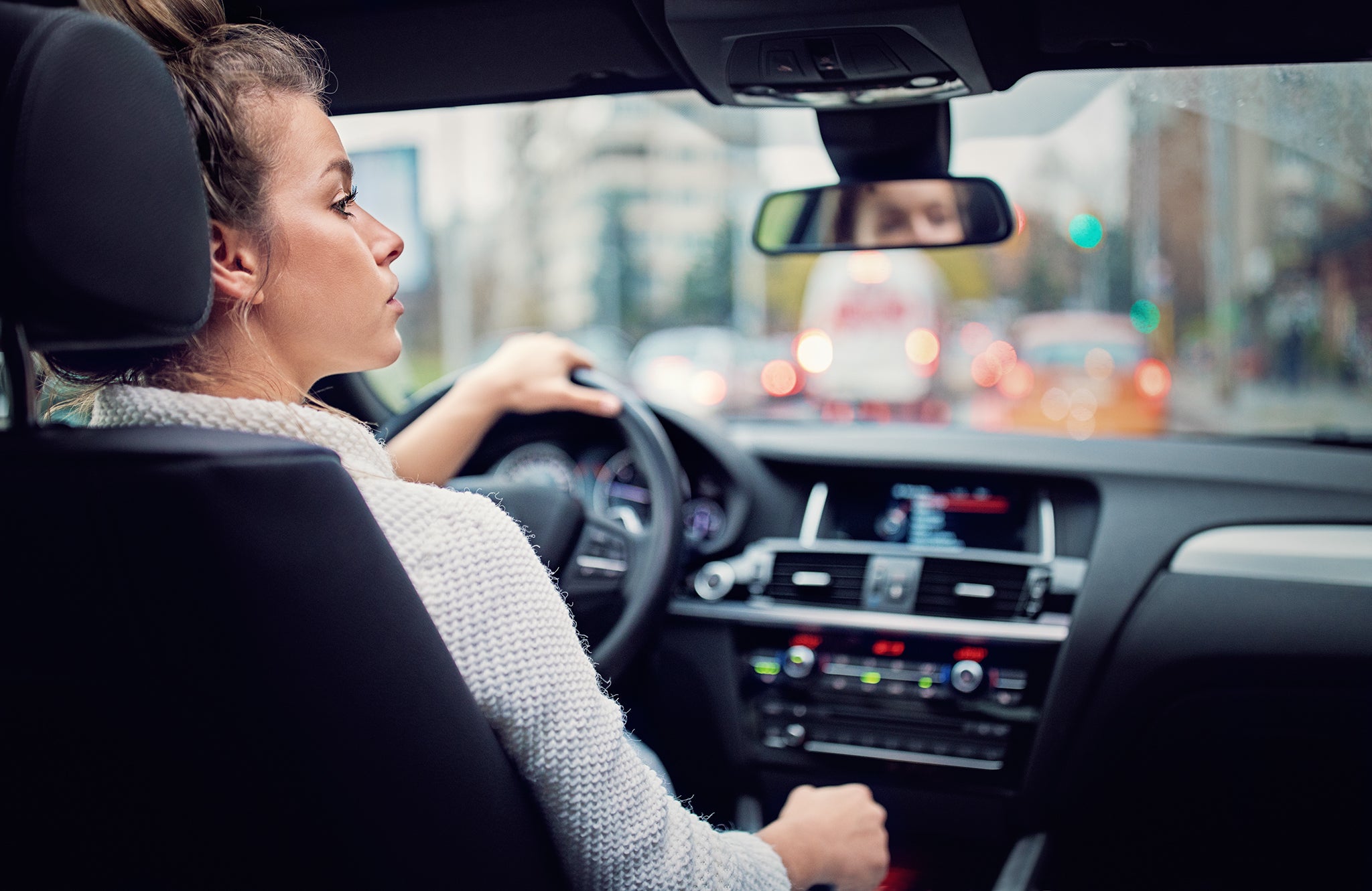 Young woman is waiting in a traffic jam in rainy day.