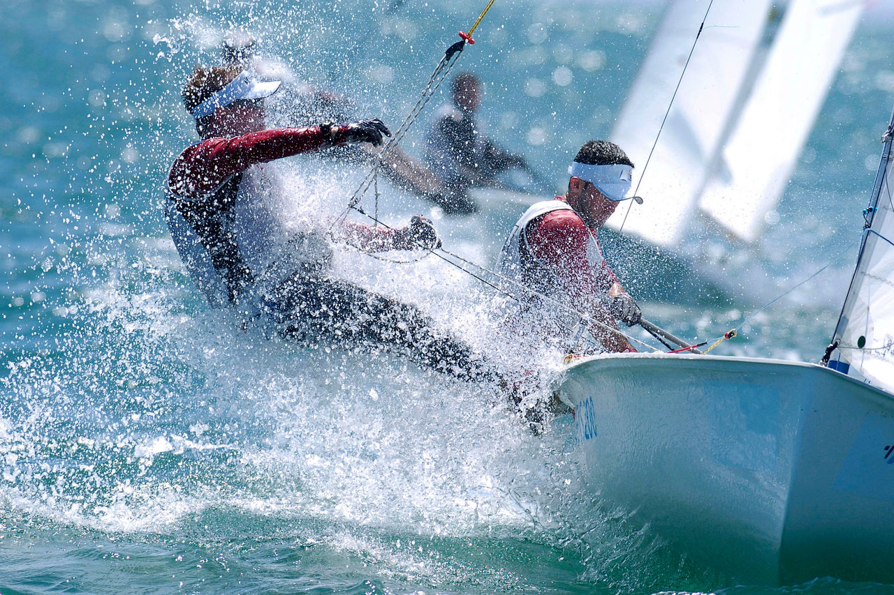 Sailors are splashed by the rough seas while sailing.